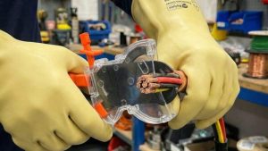 ITL insulated ratchet cutter being used with safety gloves to cut heavy-gauge electrical cable